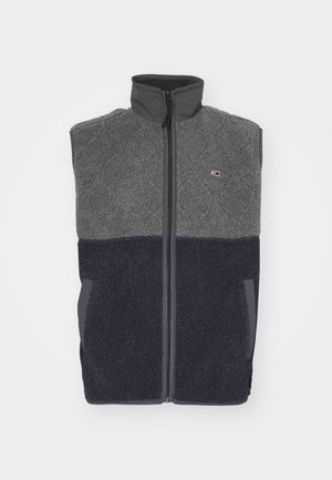 Fleece-Weste mit einer gesteppte grauen Oberseite, dunkelblauen Unterseite, hohem Kragen und Frontreißverschluss. Mit Logo-Akzent auf der oberen linken Brust.