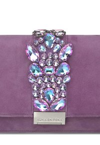 Clutch de ante púrpura con embellishments de joyas, que presenta piedras brillantes de diversas formas en tonos de azul y rosa, y una placa de logo plateada.