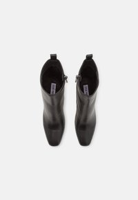 Schwarze Leder-Stiefeletten mit einem eleganten Design, spitzer Zehenform, seitlichem Reißverschluss und kurzem Ziehschlaufe, die eine glatte Textur aufweisen.