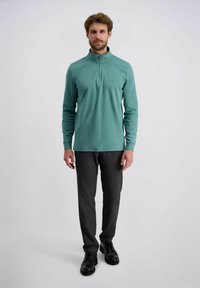 Teal lange mouwen pullover met een halve rits kraag, gemaakt van gladde stof. Draag het met donkere gebloemde broek en zwarte schoenen.