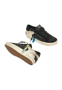 Sneaker nere e beige realizzate in materiali scamosciati e in pelle, con suola in gomma testurizzata, lacci a contrasto e tag con il marchio sul lato.