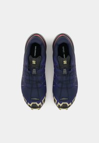 Navy blue athletic shoes with black soles, featuring a textured upper, gray accents, and elastic laces. Notable brand logo on the tongue.