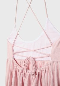 Vue de dos d'une robe rose avec des bretelles fines et un détail lacé en croix sur le haut du dos, ainsi qu'une taille froncée.