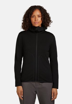 Sort lynlåsjakke med høj krave, tætsiddende design og kontrasterende syninger. Har lange ærmer og en glat tekstur.