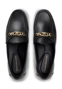 Μαύρα δερμάτινα μοκασίνια με χρυσή αλυσίδα ως διακοσμητικό στοιχείο και ραμμένες λεπτομέρειες. Το εσωτερικό διαθέτει ανάγλυφη εσωτερική σόλα για άνεση.