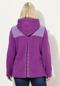 Sudadera con capucha morada con una textura acanalada en los hombros y un detalle a rayas a lo largo de la abertura trasera. Tela suave, diseño casual.