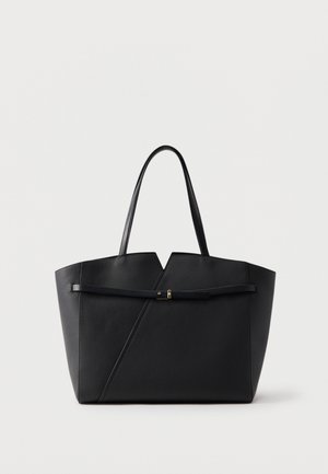 Črna usnjena torba tote z dvema ročajema, robom z ostrimi koti na vrhu in tankim vodoravnim pasom s majhno zlato zaponko spredaj.