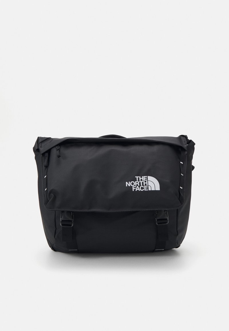 Sac besace noir North Face avec rabat, bandoulière réglable, boucles et logo blanc.