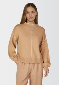 Light brown knit sweater with long sleeves, ribbed cuffs and hem, featuring a white vertical stitch detail along the front. Casual fit.