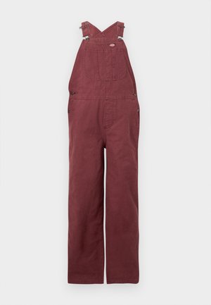 Salopette bordeaux en coton, avec des bretelles croisées dans le dos, des poches avant et des accents en métal. Texture lisse et coupe décontractée.