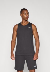 Zwarte mouwloze sporttanktop met ronde halslijn, met een klein wit Puma-logo op de linkerkant van de borst. Gecombineerd met zwarte shorts.