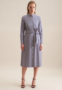 Koszula z długim rękawem w formie sukienki, w niebiesko-białą geometryczną wzory, z paskiem w talii, do kolan, z tkaniny o gładkiej teksturze.