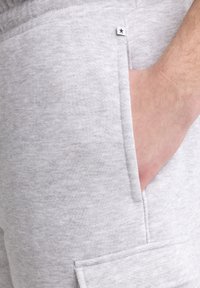 Graue Baumwollshorts mit einer Seitentasche, strukturiertem Stoff und einem kleinen Sternelement in der Nähe des Bundes. Lässiger Stil, knielang.