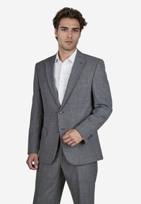 Grijze blazer met een gestructureerd ontwerp, voorzien van een visgraatpatroon, twee knopen en notch revers, gecombineerd met een wit shirt.