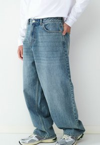 Hellblaue Denim-Jeans mit weiter Passform, hoher Taille und Fünf-Taschen-Design. Verfügen über dezentes Ausbleichen und kontrastierende Steppnähte.