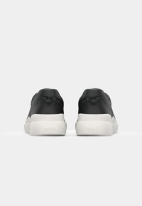 Czarne sneakersy o gładkim skórzanym wykończeniu, białych gumowych podeszwach i wyraźnym logotypie "HUGO" z tyłu, z niskim designem.