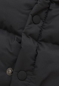 Svart puffjacka med ett kviltat mönster, slät textur och synliga svarta plastknappar med matt finish.