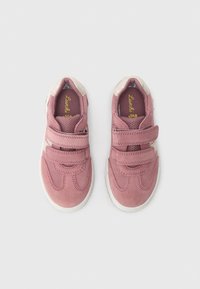 Pink suede sneakers with beige accents and two adjustable Velcro straps. Features a soft lining and white rubber soles with decorative stitching.