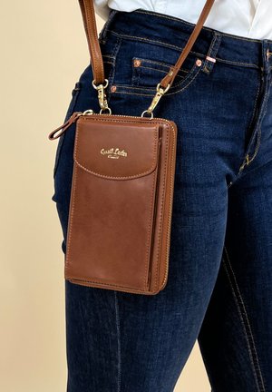 Braune Leder-Crossbody-Tasche mit goldfarbener Hardware, Reißverschluss und Fronttasche. Sie verfügt über einen abnehmbaren Trageriemen für vielseitiges Tragen.