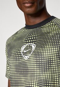 Camiseta de manga corta negra con detalles en verde lima, cuello redondo y logo blanco en el pecho. Textura suave, ajuste atlético, diseño dinámico.