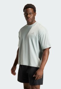 Lichtgroen oversized T-shirt met een ronde hals en korte mouwen, voorzien van een subtiel logo. Draagt comfortabel met zwarte shorts, met een losse pasvorm.