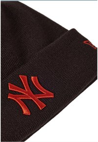 Berretto lavorato a maglia nero con un logo ricamato rosso ben visibile sul davanti. Il tessuto è morbido al tatto e presenta un design a risvolto.