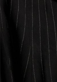 Tissu noir avec de fines rayures verticales pailletées argentées et un motif tricoté texturé.