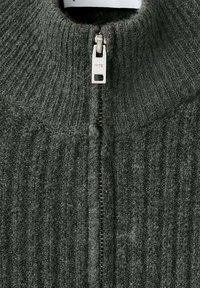 Pullover grigio scuro a costine con colletto alto, dotato di chiusura con zip silver. Tessuto morbido e testurizzato con un design casual.