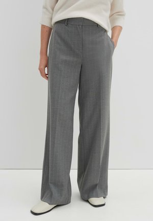 Graue, gestreifte weite Hosen mit vorderen Taschen und Gürtelschlaufen, kombiniert mit einem weichen, leichten Pullover und stilvollen cremefarbenen Schuhen.