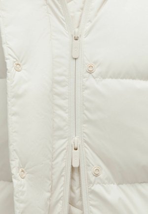 Pūkains krēmpurpurā jaka ar augstu apkakli, pilnas garuma rāvējslēdzēju un spiedpogām; tai ir gluda, spīdīga tekstūra un izšūta detaļa.