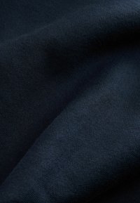Tessuto lavorato a maglia blu scuro con una consistenza morbida e una leggera lucentezza, caratterizzato da una superficie liscia e un motivo a tessitura sottile e uniforme.