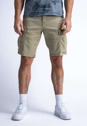 Khaki cargoshorts met zijzakken, een relaxte pasvorm en een licht gekreukt textuur. Gecombineerd met witte sneakers en crew-sokken.