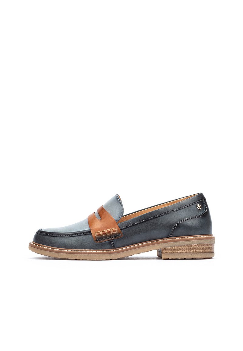 Mocasines de cuero con un cuerpo azul oscuro, cinta de acento marrón y costuras decorativas. Suela texturizada y tacón pequeño para un estilo añadido.