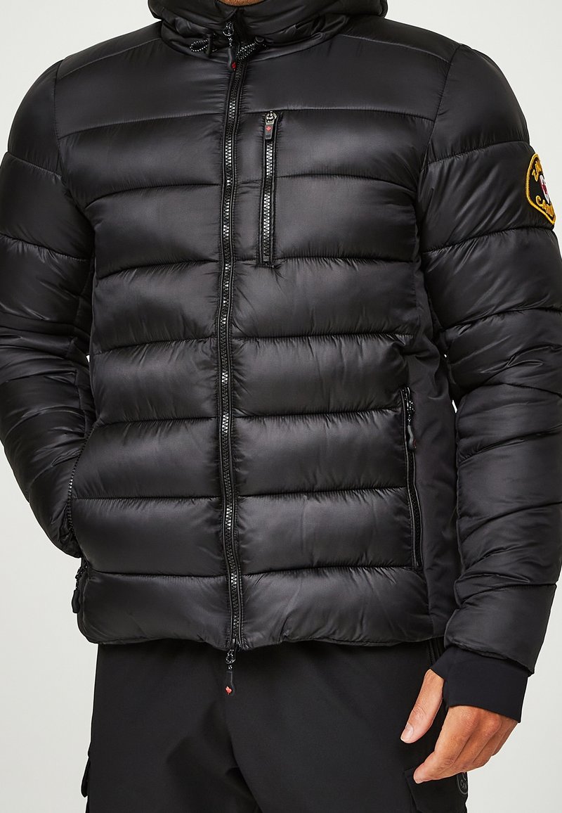 Schwarze Daunenjacke mit vertikalen Steppnähten, Kapuze, Reißverschlusstaschen und einem gestickten Logo am Ärmel. Glatte, glänzende Textur.