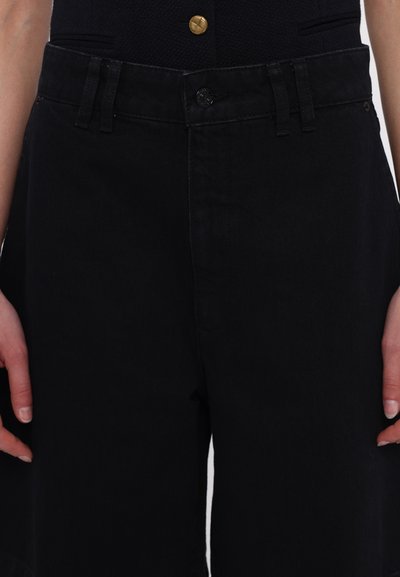 Black denim trousers with a high waist, featuring a button closure, belt loops, and a smooth texture. No visible patterns or accents.