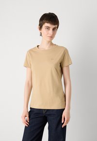 Beige T-shirt met korte mouwen van zachte katoen, met een ronde hals en een klein logo op de linkerkant van de borst. Gemaakt met donkerblauwe denim.