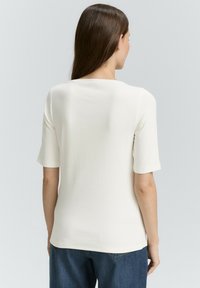Witte korte mouwen top met een ronde halslijn, zachte textuur en een aansluitend ontwerp, gecombineerd met donkerblauwe denim jeans.