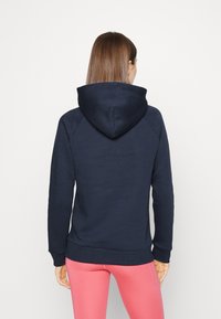 Felpa navy con cappuccio regolabile, realizzata in un materiale morbido. Presenta maniche raglan e un orlo a coste, abbinata a leggings rosa.