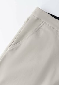 Beige broek met een gladde textuur, schuin zijzak en een verborgen rits in de tailleband voor een nette afwerking.