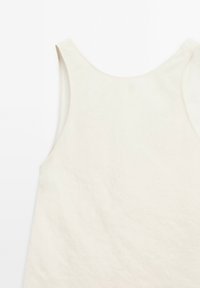 Vaalea beige sansihihainen paita, jossa on sileä pinta, pyöreä kaula-aukko ja leveät kädentie, esittelee minimalista muotoilua.