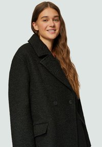 Zwarte geprofileerde jas met een grote kraag, dubbele knopen en zijzakken, met een warme en gezellige uitstraling.