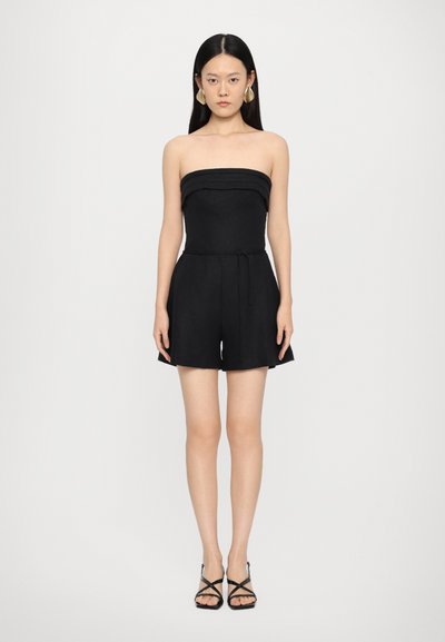 Sort strapless romper med en tætsiddende bodice og flagrende shorts. Fremstillet af struktureret stof, har den en samlet halsudskæring og en snoreliv.