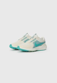 Nike Laufschuhe mit einem cremefarbenen Obermaterial, türkisfarbenen Akzenten, Netz- und Synthetiktexturen sowie einer flexiblen Gummisohle.