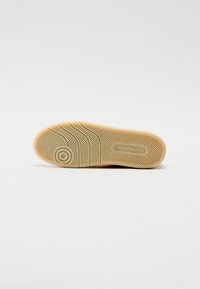 Beige gummisåle med fiskebensmønster og sirkulært logodetalj. Jevn tekstur med forskjellige mønster for bedre grep.