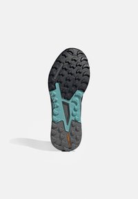 Suola in gomma nera con tacche profonde e un distintivo accento turchese in un design a zigzag. Presenta il marchio "Continental".