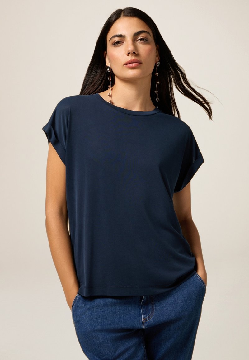 Top blu navy a maniche corte in un tessuto morbido e leggero, con scollatura rotonda e una vestibilità comoda, abbinato a jeans in denim.