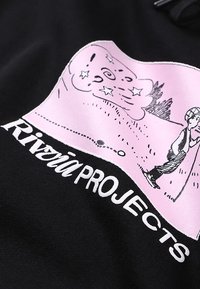 Tissu noir avec un grand motif rose représentant une silhouette et des étoiles. Le texte « Riviera PROJECTS » est imprimé en blanc sous le motif.