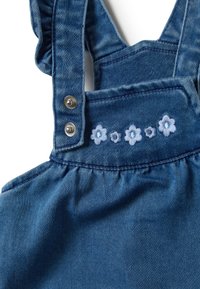 Jeanslatzhosen mit verstellbaren Trägern, hellblauer Floralstickerei auf der Brust und silbernen Druckknöpfen. Weicher, strukturierter Stoff.