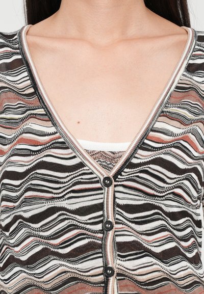 Cardigan lavorato a maglia con scollo a V, motivo ondulato multicolore in bianco, nero e tonalità di rosa. Cinque bottoni neri decorano la parte anteriore.