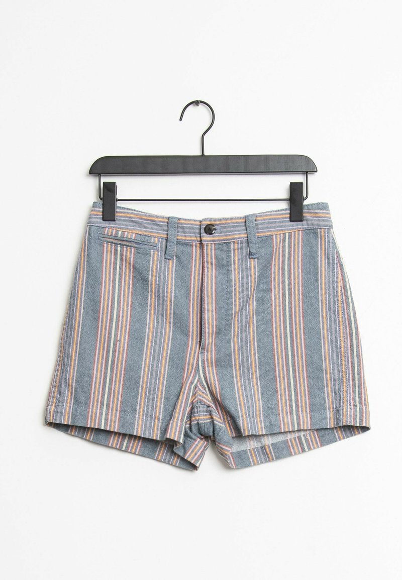 Shorts bleus avec des rayures verticales orange, blanches et violettes suspendus à un cintre noir à pince sur un fond blanc.